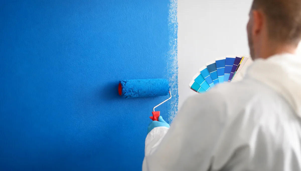 Peintre appliquant une peinture bleue au rouleau sur un mur